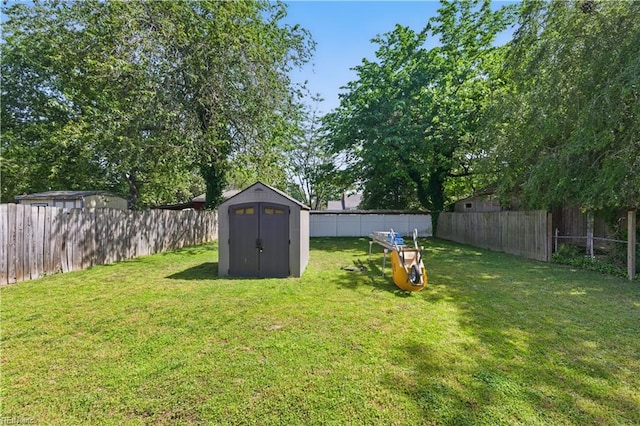 view of yard with an outbuilding, a fenced backyard, and a storage unit