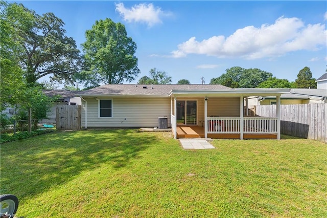 back of property with a deck, a lawn, a fenced backyard, and central AC
