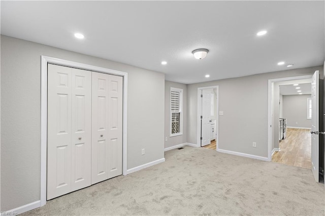 unfurnished bedroom featuring baseboards, a closet, recessed lighting, and light colored carpet