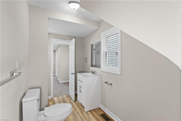 bathroom featuring toilet, wood finished floors, vanity, visible vents, and baseboards