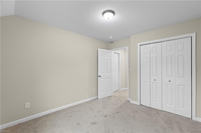 unfurnished bedroom with a textured ceiling, carpet, baseboards, and a closet