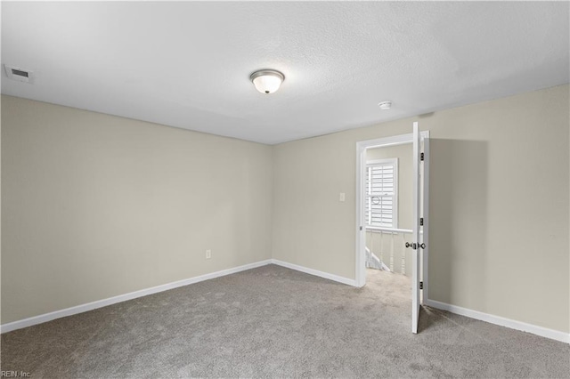 carpeted spare room featuring baseboards, visible vents, and a textured ceiling