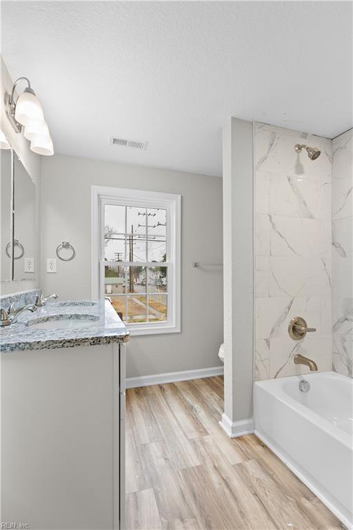 full bathroom featuring shower / bath combination, baseboards, visible vents, vanity, and wood finished floors