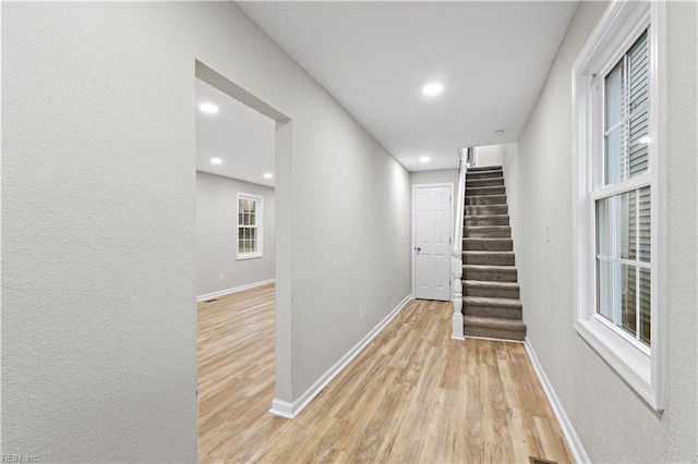 corridor featuring light wood finished floors, stairs, baseboards, and recessed lighting