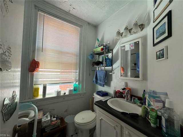 half bathroom with a textured ceiling, vanity, and toilet