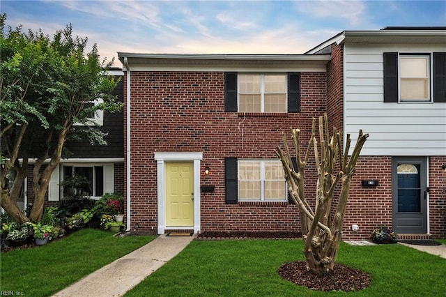 view of property featuring a front yard and brick siding