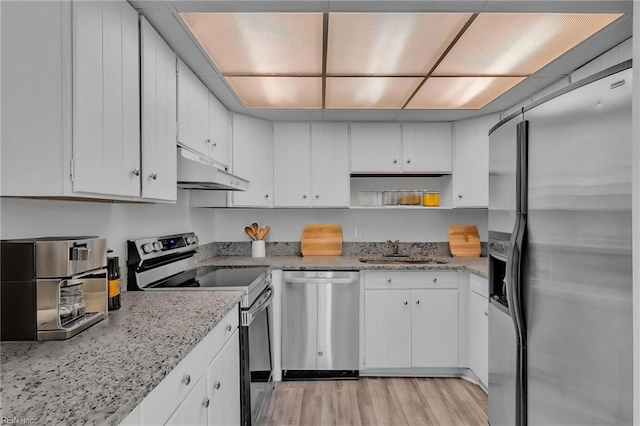 kitchen featuring appliances with stainless steel finishes, under cabinet range hood, a sink, white cabinetry, and light wood-style flooring