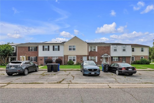 townhome / multi-family property with brick siding and uncovered parking