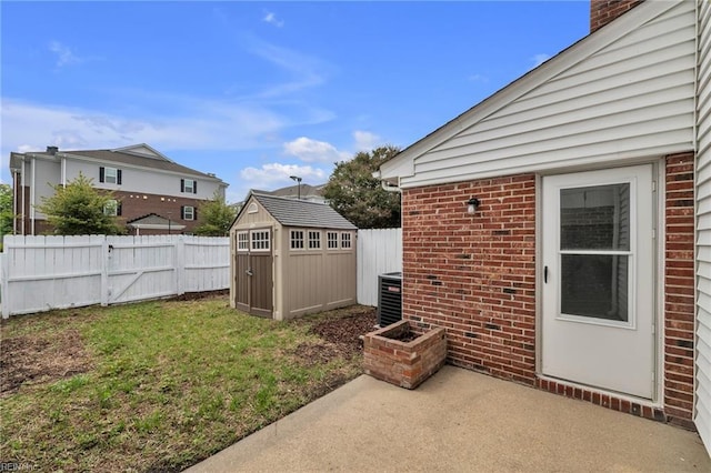 fenced backyard featuring a patio area, a storage unit, an outbuilding, and central AC unit