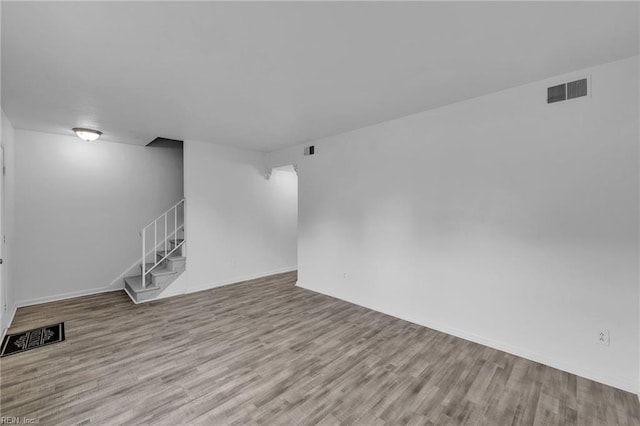 unfurnished living room with wood finished floors, stairway, and baseboards