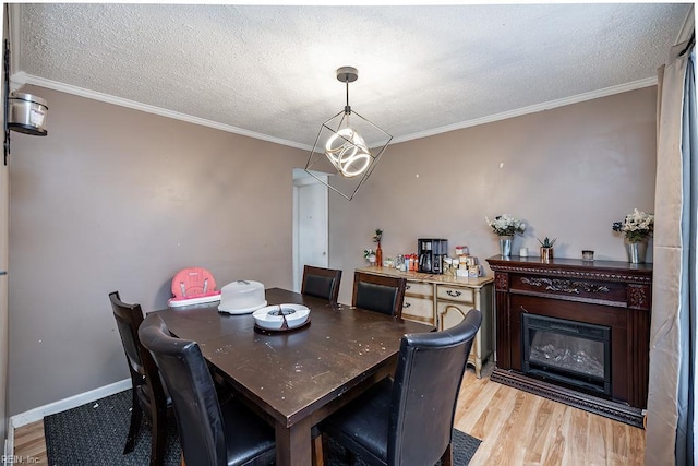 dining space with ornamental molding, light wood-style flooring, and a textured ceiling