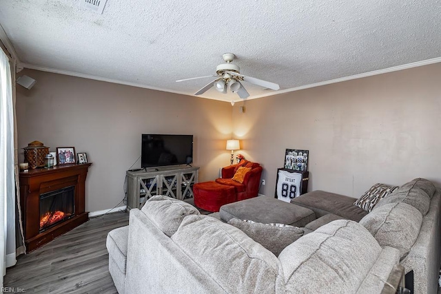 living area featuring ornamental molding, a textured ceiling, a ceiling fan, and wood finished floors