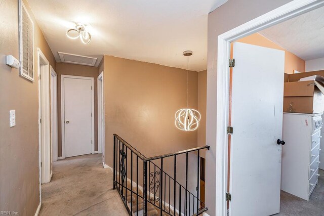 hall with carpet, an upstairs landing, and visible vents
