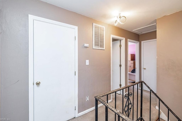 hallway featuring attic access, visible vents, baseboards, and light carpet