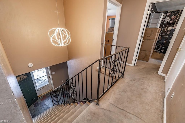 stairway featuring carpet flooring and a notable chandelier