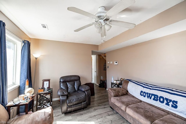 living area with ceiling fan, baseboards, light wood-type flooring, and visible vents