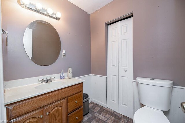 bathroom with a closet, toilet, and vanity