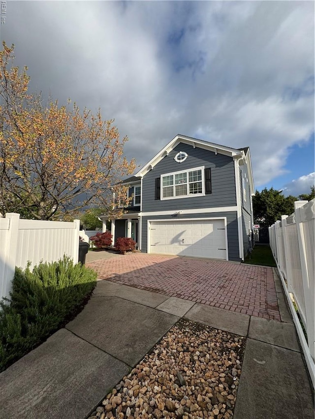 exterior space featuring decorative driveway, fence, and a garage