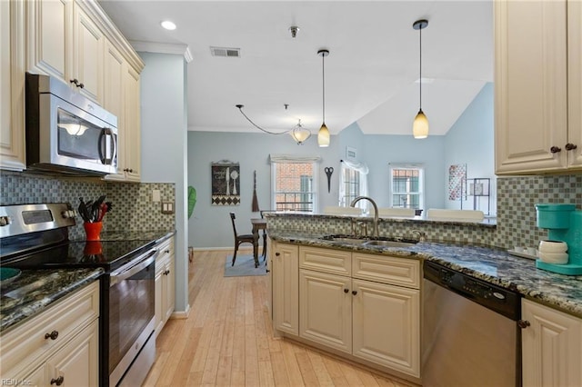 kitchen featuring a sink, a peninsula, stainless steel appliances, tasteful backsplash, and visible vents