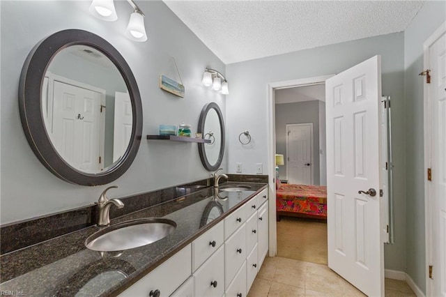 full bath with double vanity, a textured ceiling, tile patterned flooring, and a sink