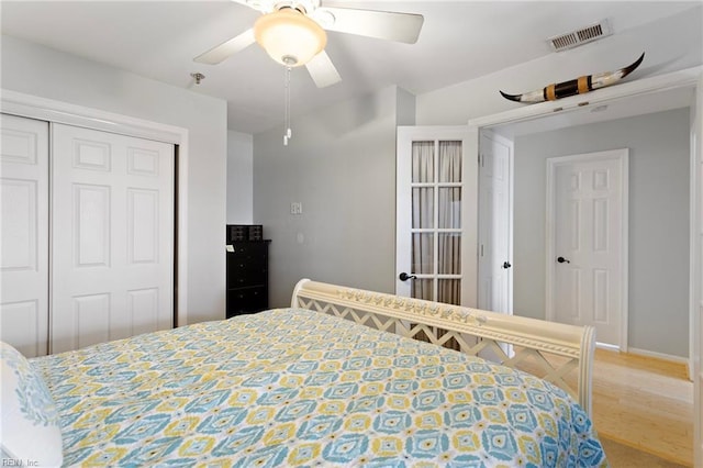 bedroom featuring a closet, baseboards, ceiling fan, visible vents, and wood finished floors