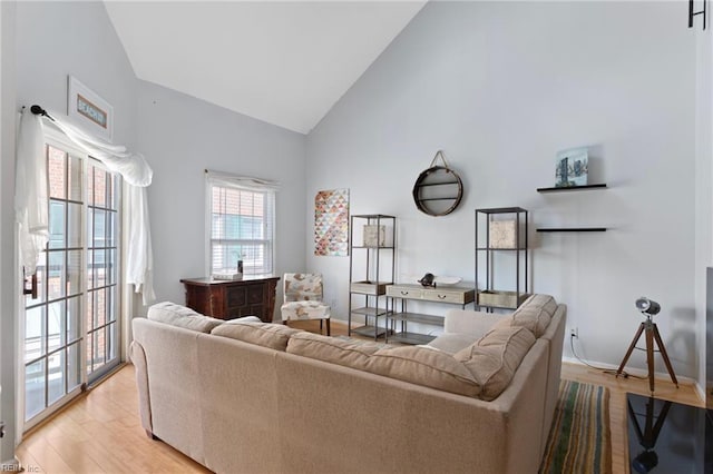 living area featuring baseboards, high vaulted ceiling, and light wood-style floors