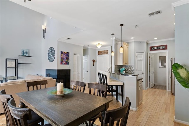dining room featuring recessed lighting, baseboards, ornamental molding, light wood finished floors, and visible vents