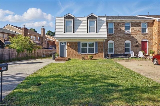 view of front facade with fence, a front lawn, brick siding, and concrete driveway