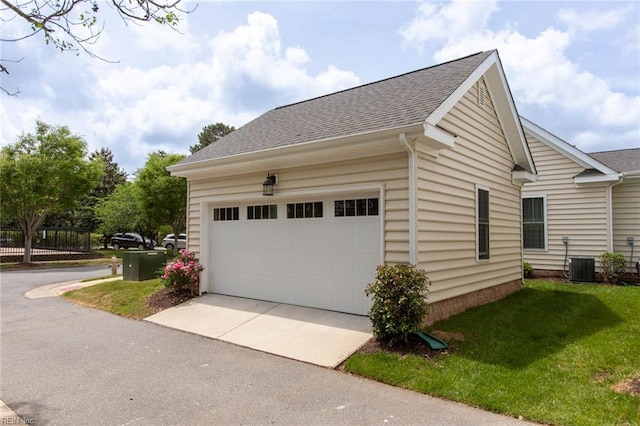 view of side of home featuring a shingled roof, concrete driveway, central AC unit, and a garage