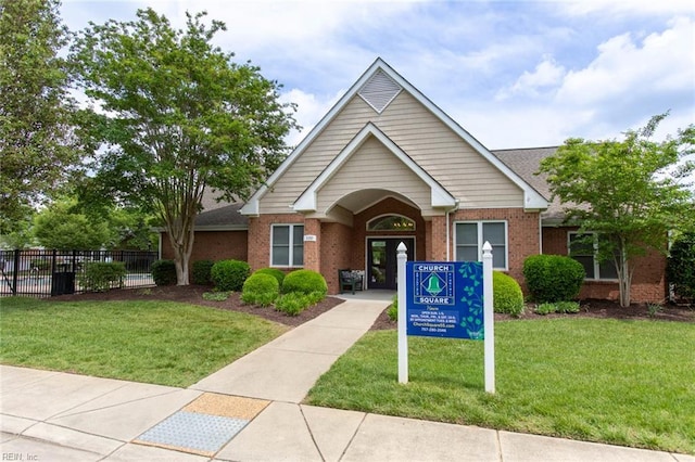 view of front of home with brick siding, fence, and a front yard
