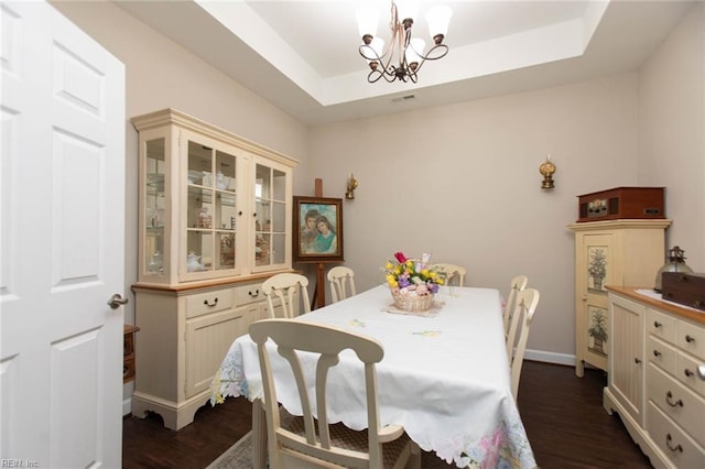 dining area with a tray ceiling, baseboards, a chandelier, and dark wood-type flooring