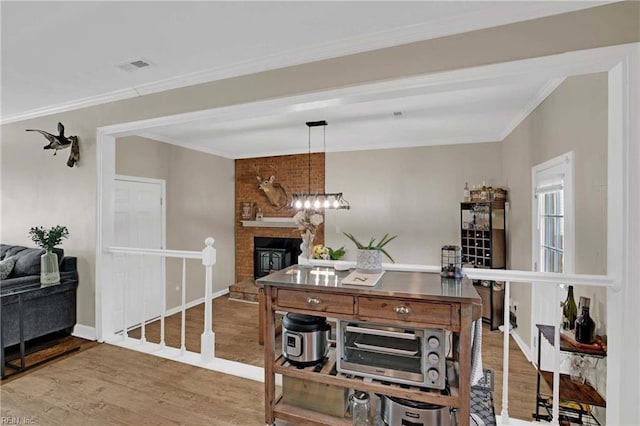 office with wood finished floors, ornamental molding, a chandelier, a large fireplace, and baseboards
