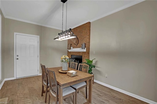 dining room featuring baseboards, wood finished floors, ornamental molding, and a fireplace