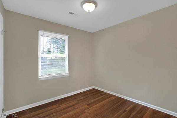 spare room featuring dark wood-style flooring and baseboards