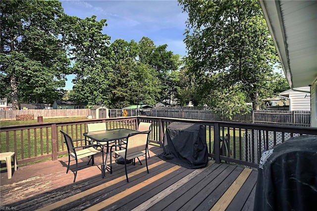 deck featuring a shed, outdoor dining space, and an outdoor structure