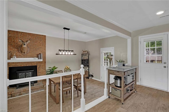 dining area featuring light wood-style floors, a fireplace, baseboards, and crown molding