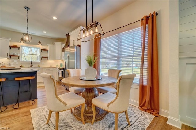 dining space with a chandelier, light wood-style flooring, baseboards, and recessed lighting