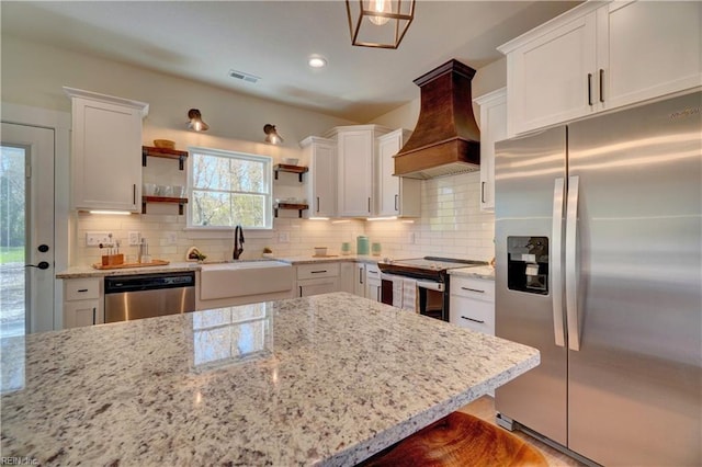 kitchen featuring a sink, stainless steel appliances, open shelves, visible vents, and custom exhaust hood