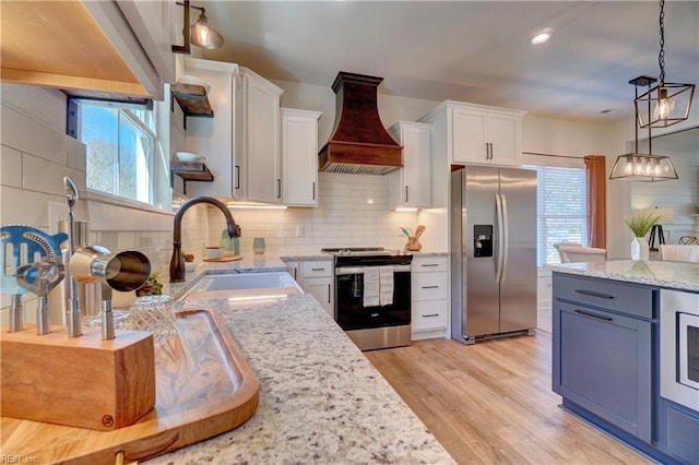 kitchen featuring stainless steel appliances, custom exhaust hood, a sink, and plenty of natural light