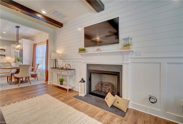 living area with wood finished floors, a fireplace, visible vents, beamed ceiling, and recessed lighting