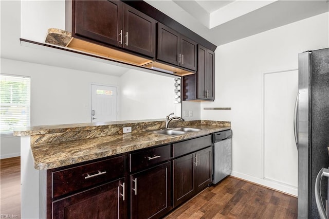kitchen with stainless steel appliances, a sink, dark wood-style flooring, a peninsula, and dark brown cabinets
