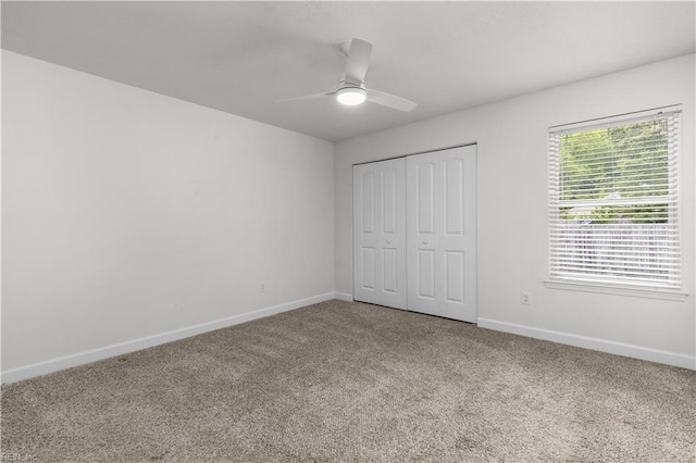 unfurnished bedroom with carpet flooring, baseboards, a closet, and a ceiling fan