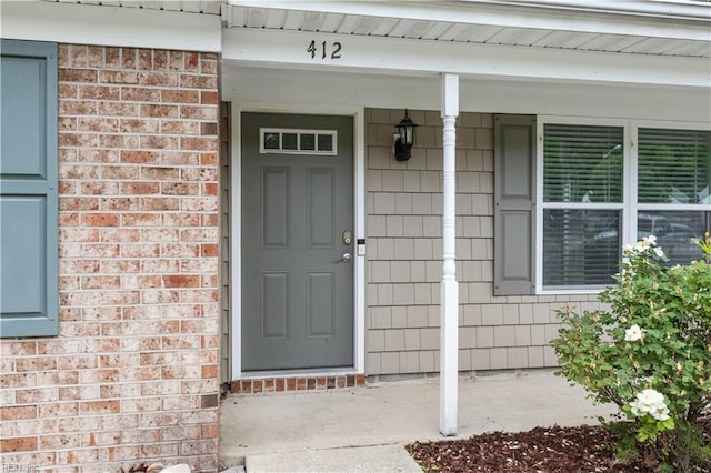 property entrance featuring brick siding and covered porch