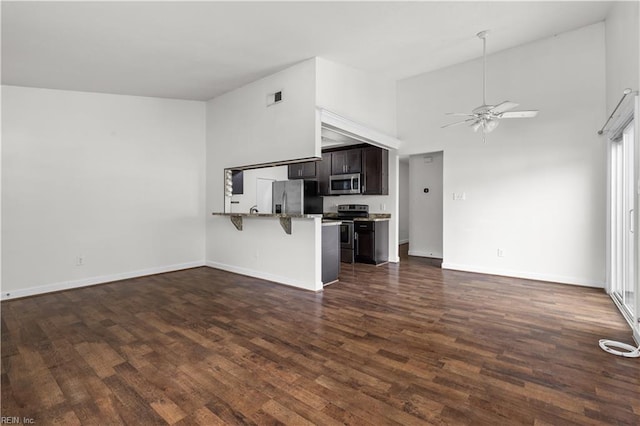 unfurnished living room featuring dark wood-style flooring, ceiling fan, baseboards, and high vaulted ceiling