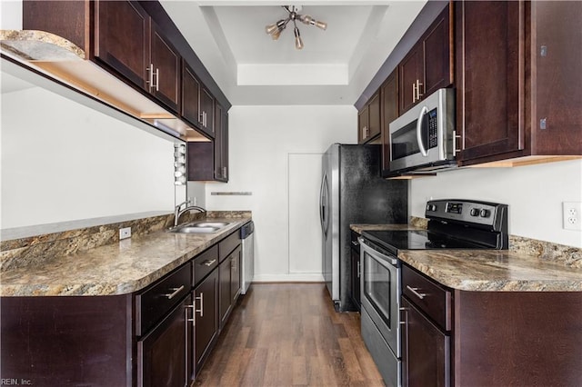 kitchen featuring appliances with stainless steel finishes, a sink, a raised ceiling, dark wood-type flooring, and baseboards