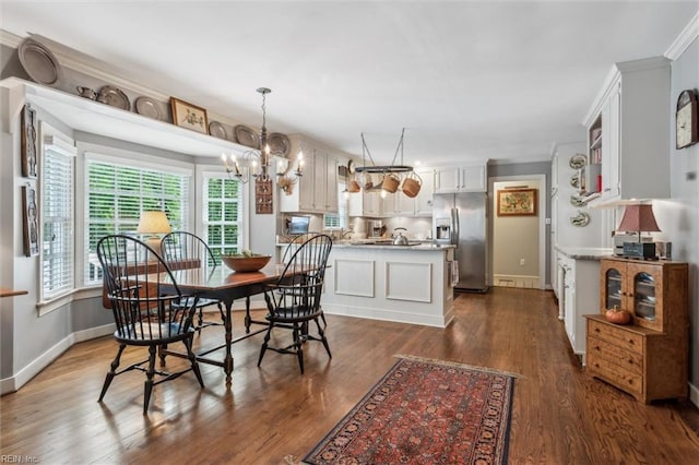 dining area featuring dark wood-style flooring, a chandelier, and baseboards
