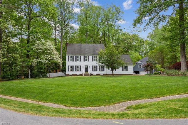 colonial inspired home featuring entry steps, a front lawn, and view of scattered trees