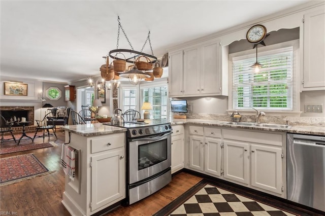 kitchen with stainless steel appliances, a peninsula, a sink, and healthy amount of natural light