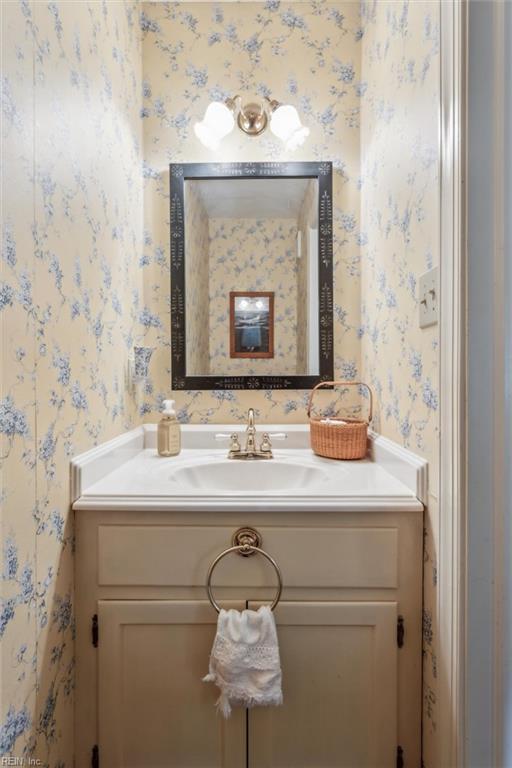 bathroom with wallpapered walls and vanity