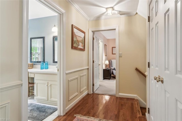 hall with wood finished floors, ornamental molding, and a sink